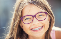 Happy smiling girl with dental braces and glasses.